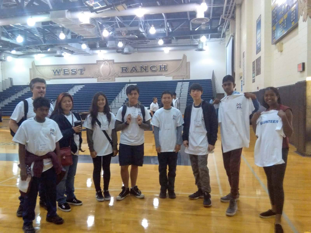 Team members and coaches stand inside West Ranch High School's gym wearing FIRST FLL volunteer shirts